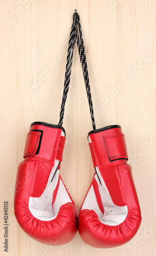 Red boxing gloves hanging on wooden background © Africa Studio