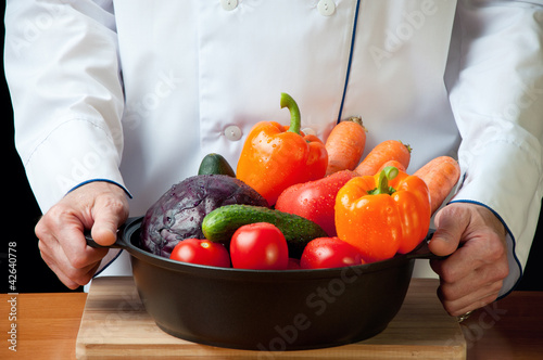 Chef holding a frying pan with variety of fresh vegetables