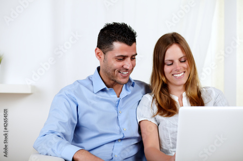 Lovely couple smiling and using a laptop