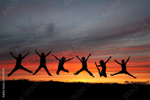 silhouette of teenagers jumping in sunset for fun