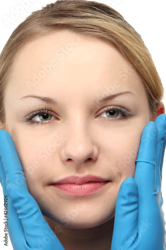 Hands of a surgeon touching the face of a beautiful woman