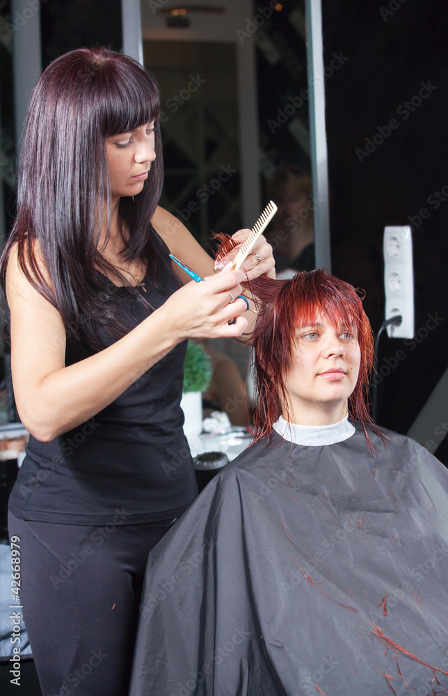 Fototapeta premium hair stylist cutting woman hair in salon