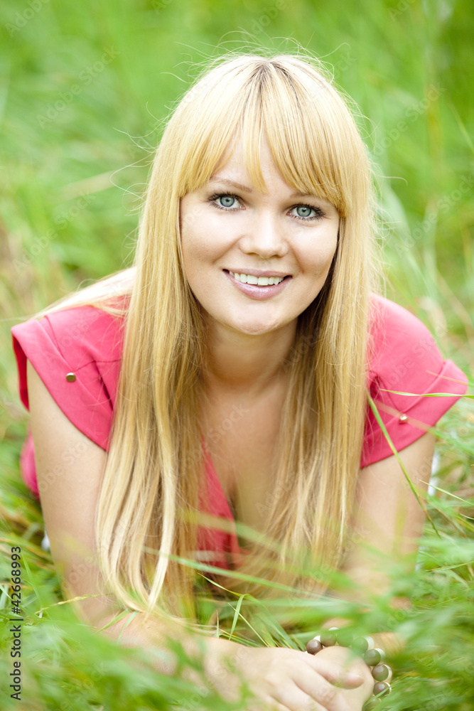Blonde girl at green grass in the park.
