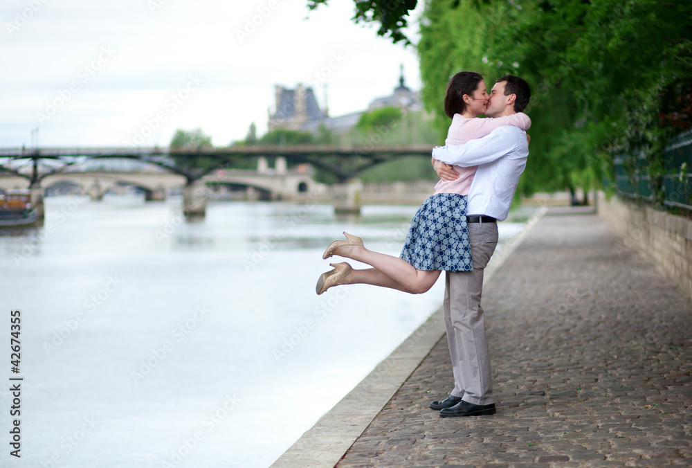Happy romantic couple is hugging near the Seine, girl is jumping