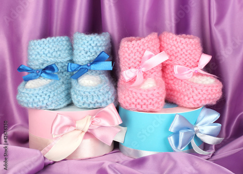 pink and blue baby boots and gifts on silk background.