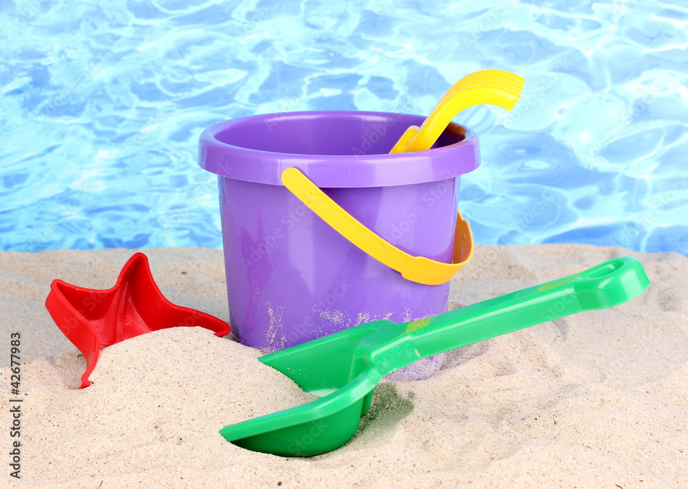 Children's beach toys on sand on water background Children's beach toys on sand on water background