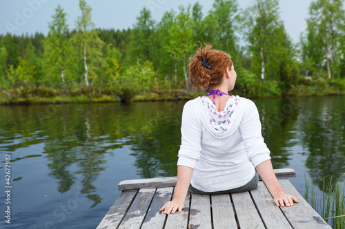Young woman turning back sitting on wooden boards © Kekyalyaynen