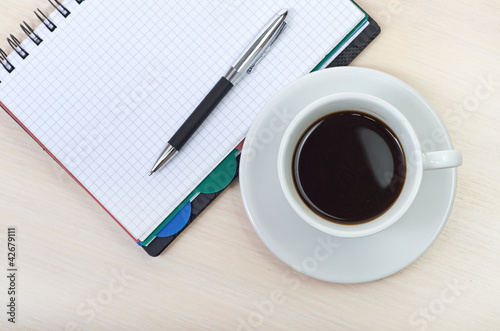 Coffee cup with note book on table