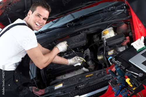 Auto mechanic checking oil.