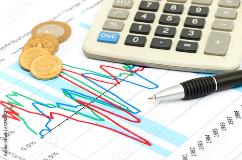 Calculator, coins and pen laying on chart. Concept of finance. photo