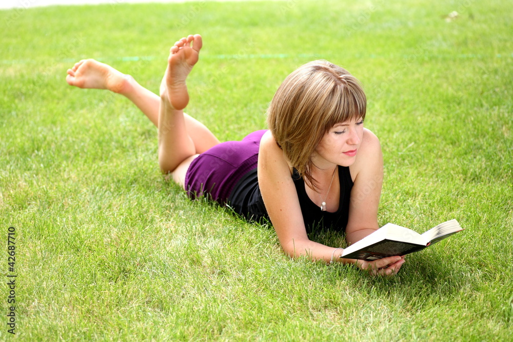 Young happy woman looking at the camera while reading a book Young happy woman looking at the camera while reading a book