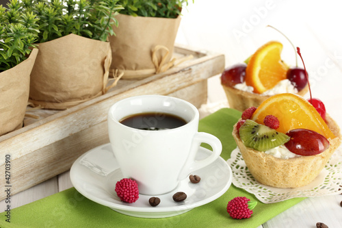 cup of coffee and sweet cakes with fruits on wooden table