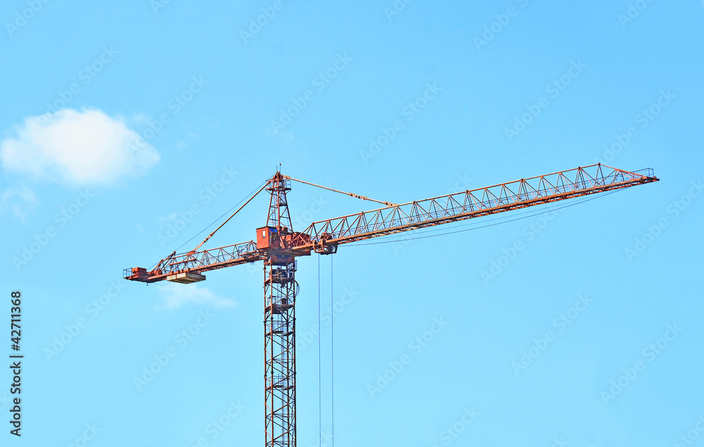 Red construction tower crane against blue sky