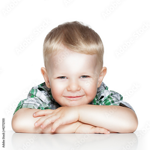 Portrait of a cute little boy smiling while sitting at table, is