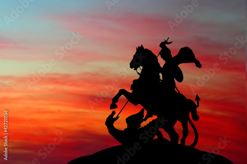Saint George and the Dragon on sunset background