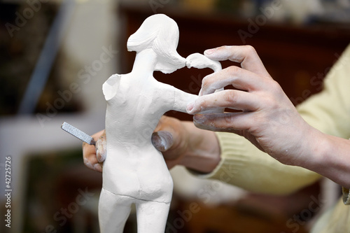 Obraz na plátně Hands of sculptor works with plaster statuette.