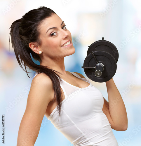 portrait of a young pretty woman holding weights and doing fitne #42745781