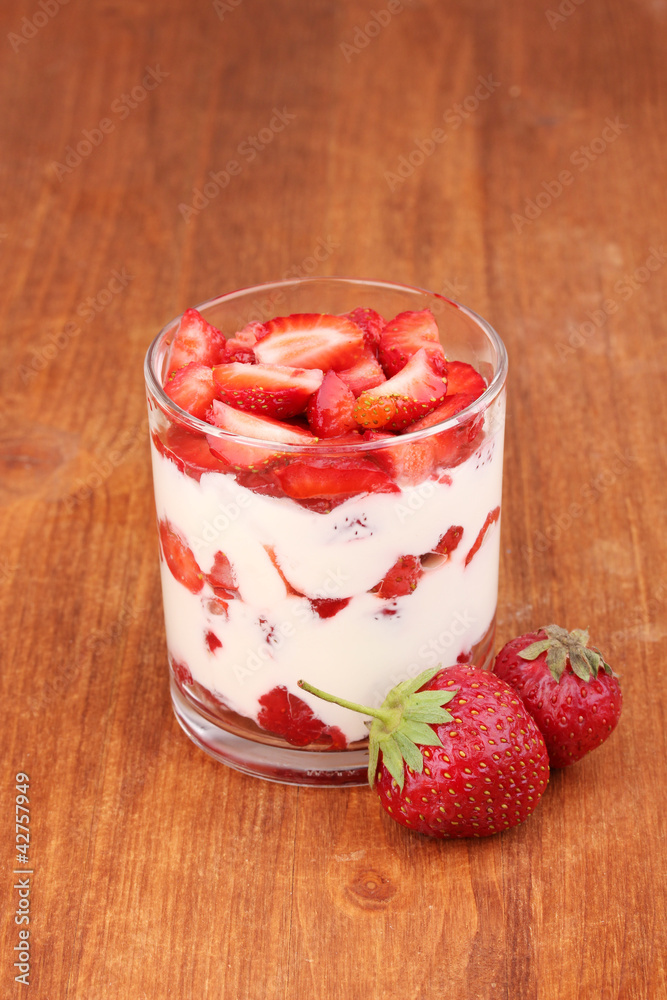 Glass of ripe strawberries with cream on wooden background Glass of ripe strawberries with cream on wooden background