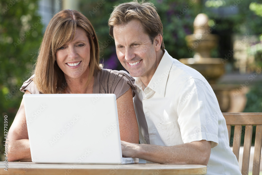 Man & Woman Couple Using Laptop Computer In Garden Man & Woman Couple Using Laptop Computer In Garden