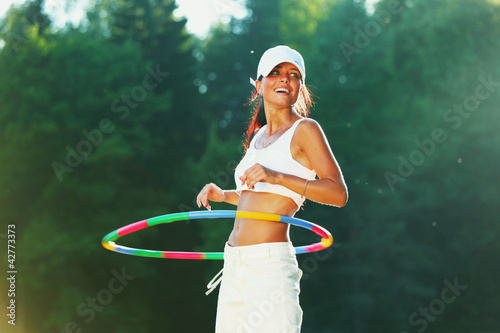woman rotates hula hoop on nature background photo