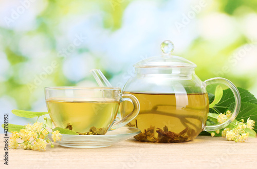 teapot and cup with linden tea and flowers