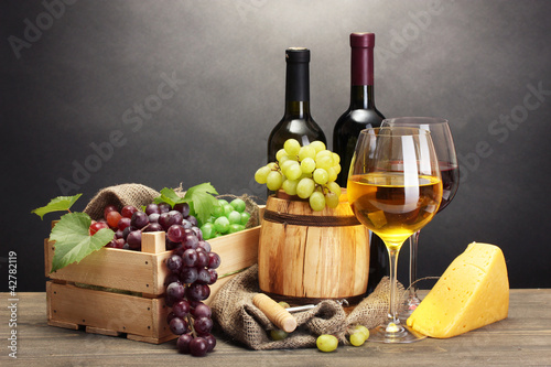 barrel, bottles and glasses of wine, cheese and ripe grapes