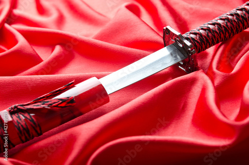 Japanese sword takana on red satin background photo