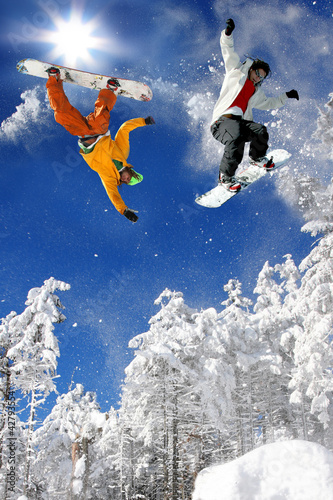 Snowboarders  jumping against blue sky