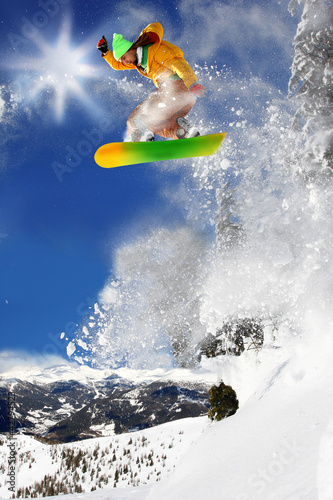 Snowboarder jumping against blue sky