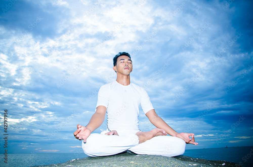 Fototapeta premium Asian man doing yoga on the beach