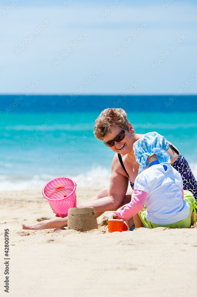 Grandmother playing with granddaughter on beach toys Grandmother playing with granddaughter on beach toys