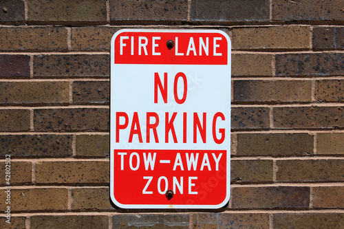 No parking sign posted on a brick wall