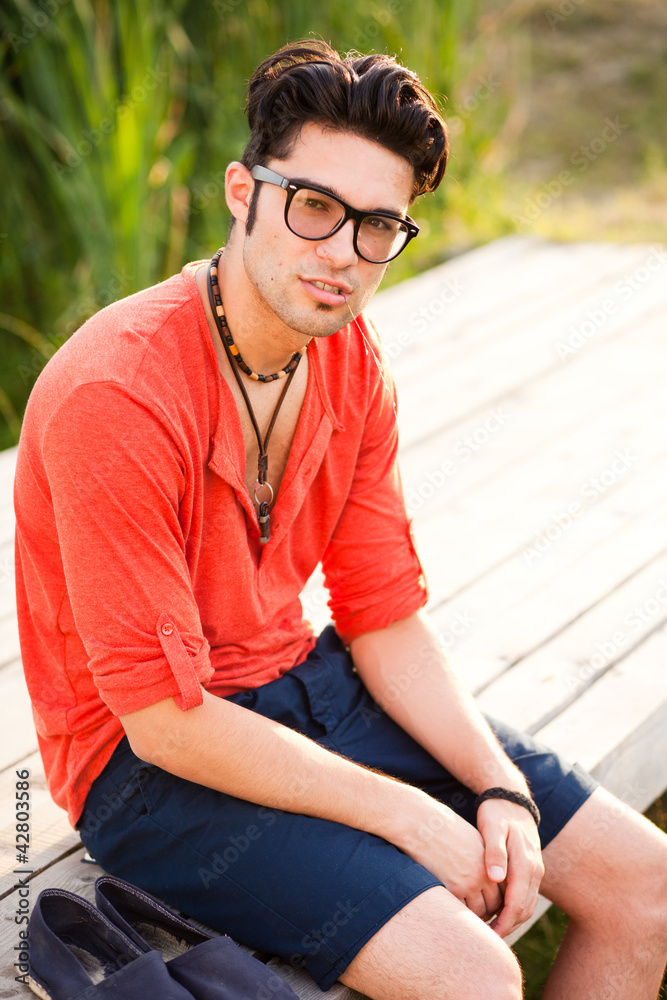 handsome man standing on a bridge by the lake handsome man standing on a bridge by the lake