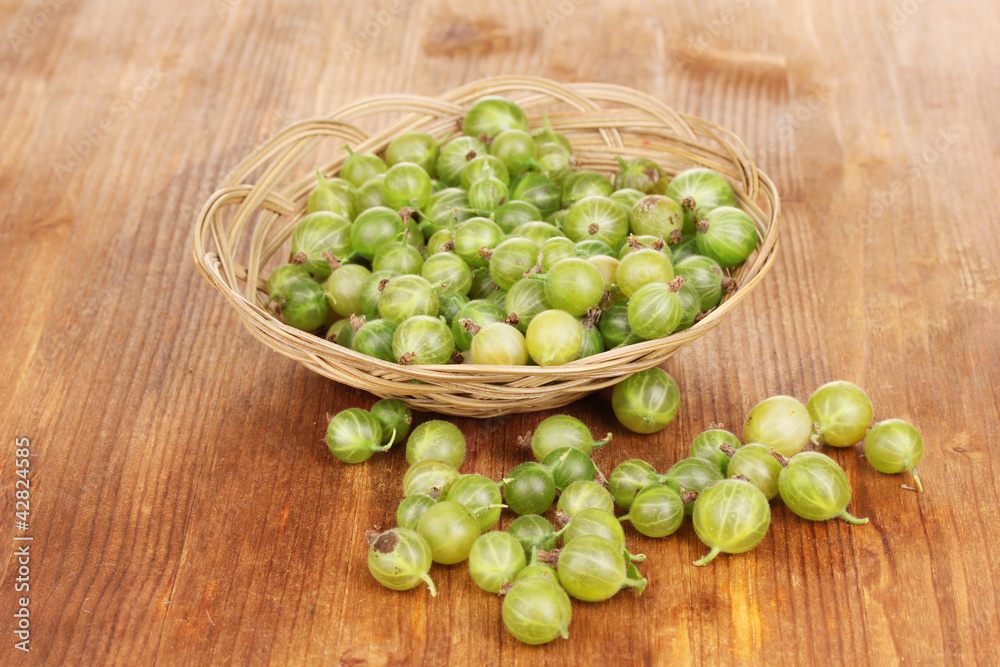 Green gooseberry in basket on wooden background Green gooseberry in basket on wooden background