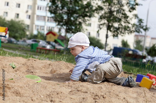 Child crawling in sandbox