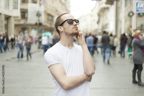 Young Man with sunglasses and cell phone walking