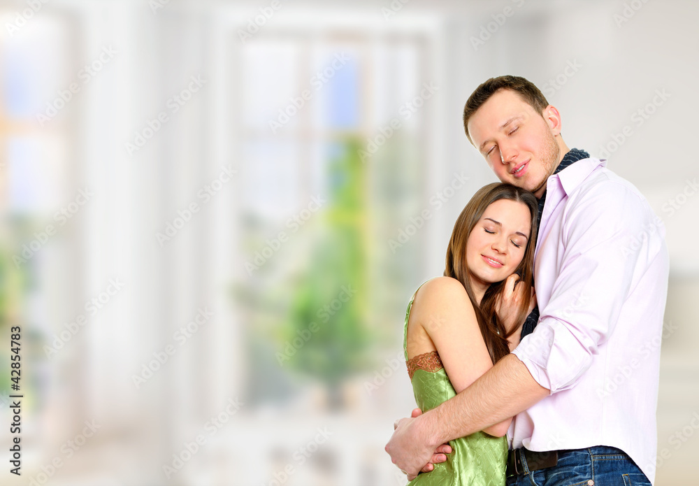Cosy young couple embracing inside new apartment and planning to