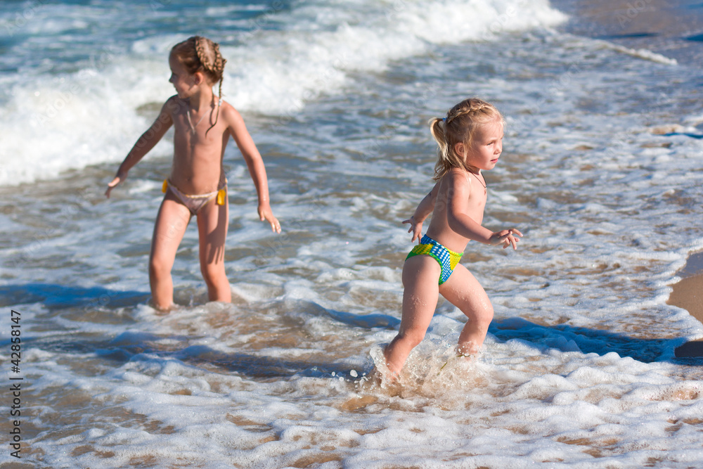 Little girls in the spray of waves at sea
