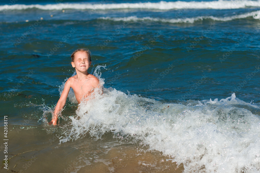 Little girl crying in the spray of waves at sea