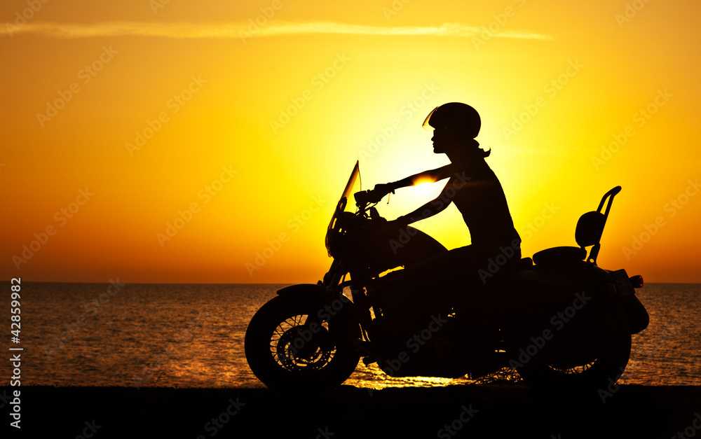 Naklejka premium Woman biker over sunset