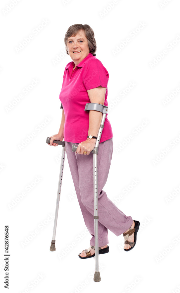 Smiling senior woman walking with crutches Smiling senior woman walking with crutches