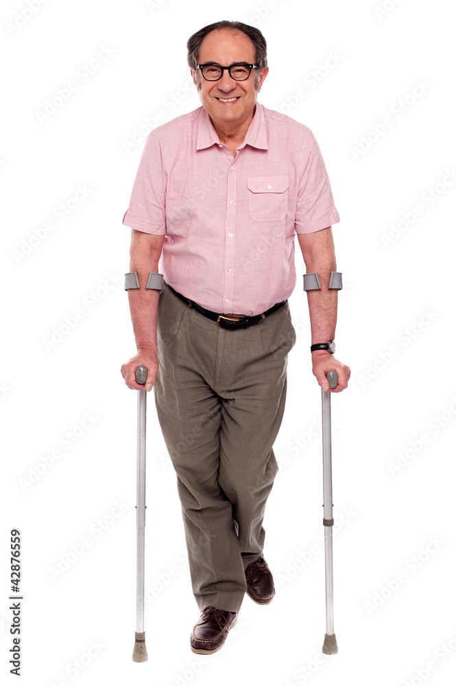 Smiling senior man walking with two crutches Smiling senior man walking with two crutches