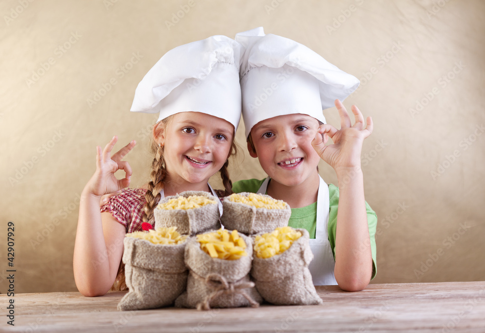 Kids with chef hats and pasta varieties - traditional food Kids with chef hats and pasta varieties - traditional food