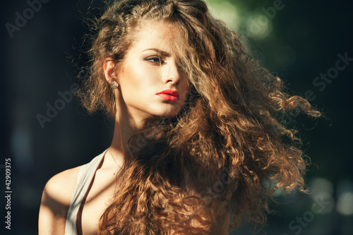 Beautiful young woman with gorgeous curly hair outdoors