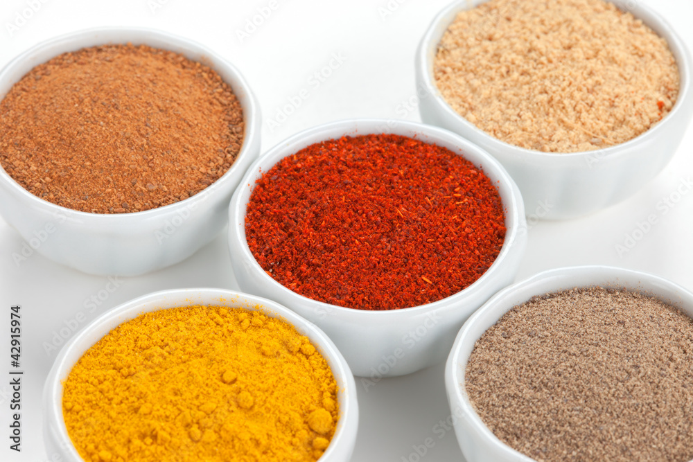 Different spices in white bowls isolated on white background. Different spices in white bowls isolated on white background.