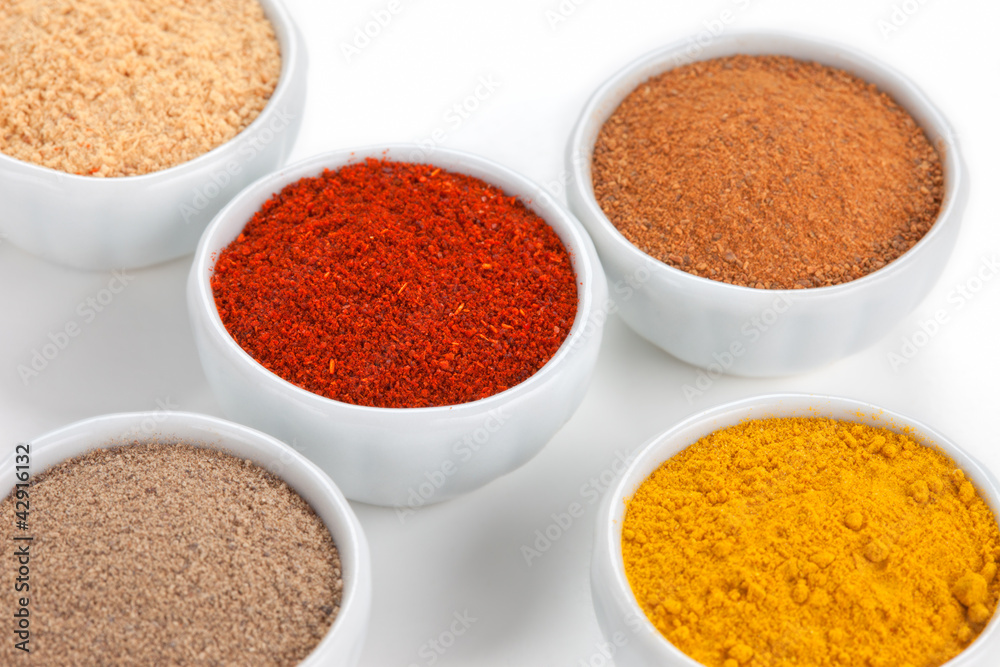  Different spices in white bowls isolated on white background.