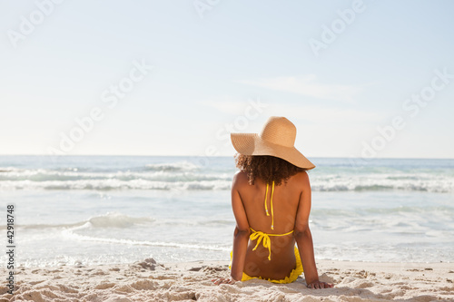 Young attractive woman looking at the ocean while sunbathing