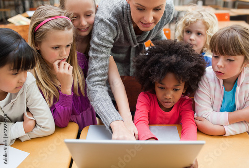 Teacher explaining laptop to students photo