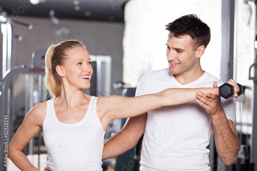 Trainer helping a woman work out with dumbbells