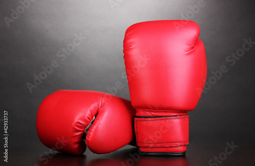 Red boxing gloves on grey background © Africa Studio